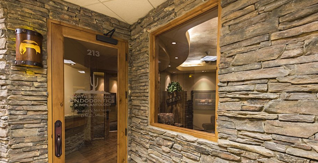 Modern dental office entrance with stone accent walls and wooden door frame in North Scottsdale.