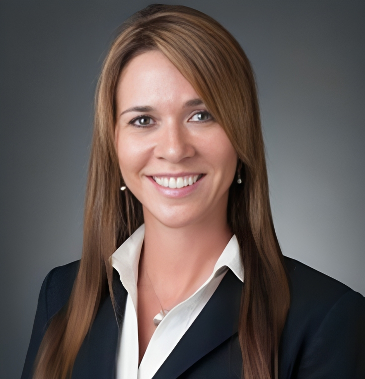 Professional headshot of woman in business attire smiling at camera, neutral background.