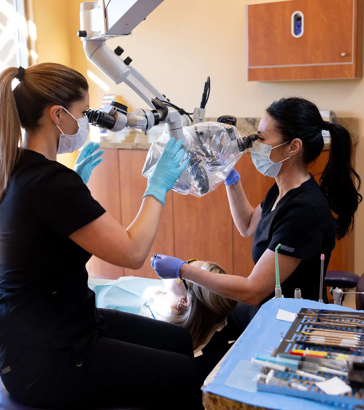 Two dental professionals examine a patient using an intraoral camera in a modern endodontic treatment room.