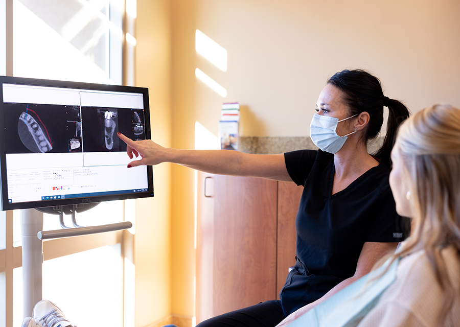 Dentist discussing X-rays with patient in modern dental office treatment room.